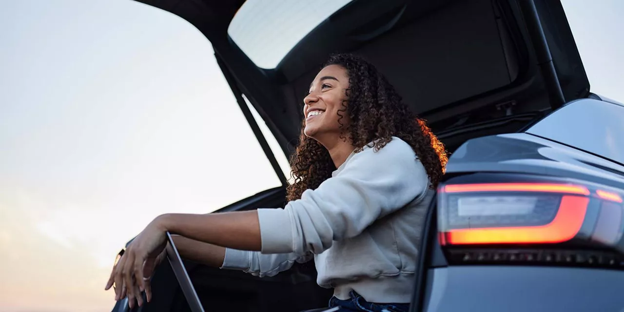 Eine Frau sitzt in einem Auto und öffnet die Tür.
